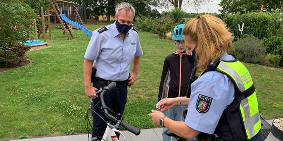 Polizisten erklären einem Kind etwas zum Fahrrad