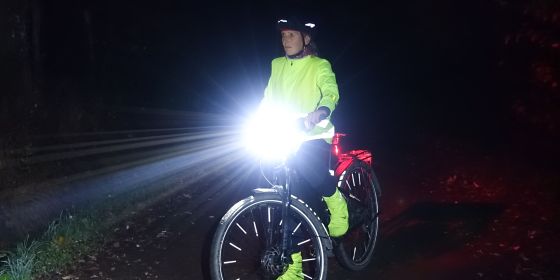 Radfahrer bei Dunkelheit mit Leuchtkleidung und hellem Scheinwerfer